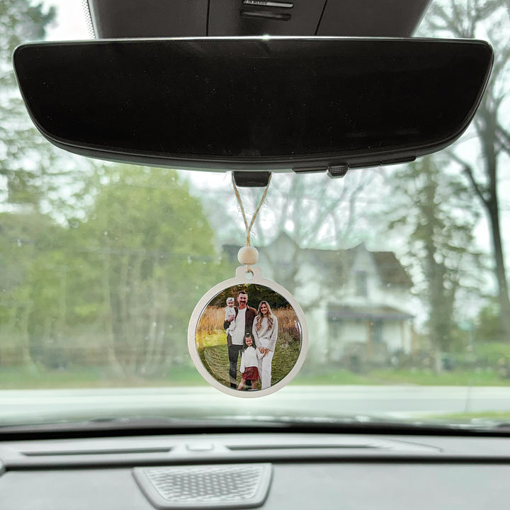 Personalized family photo ornament hanging from a car rearview mirror