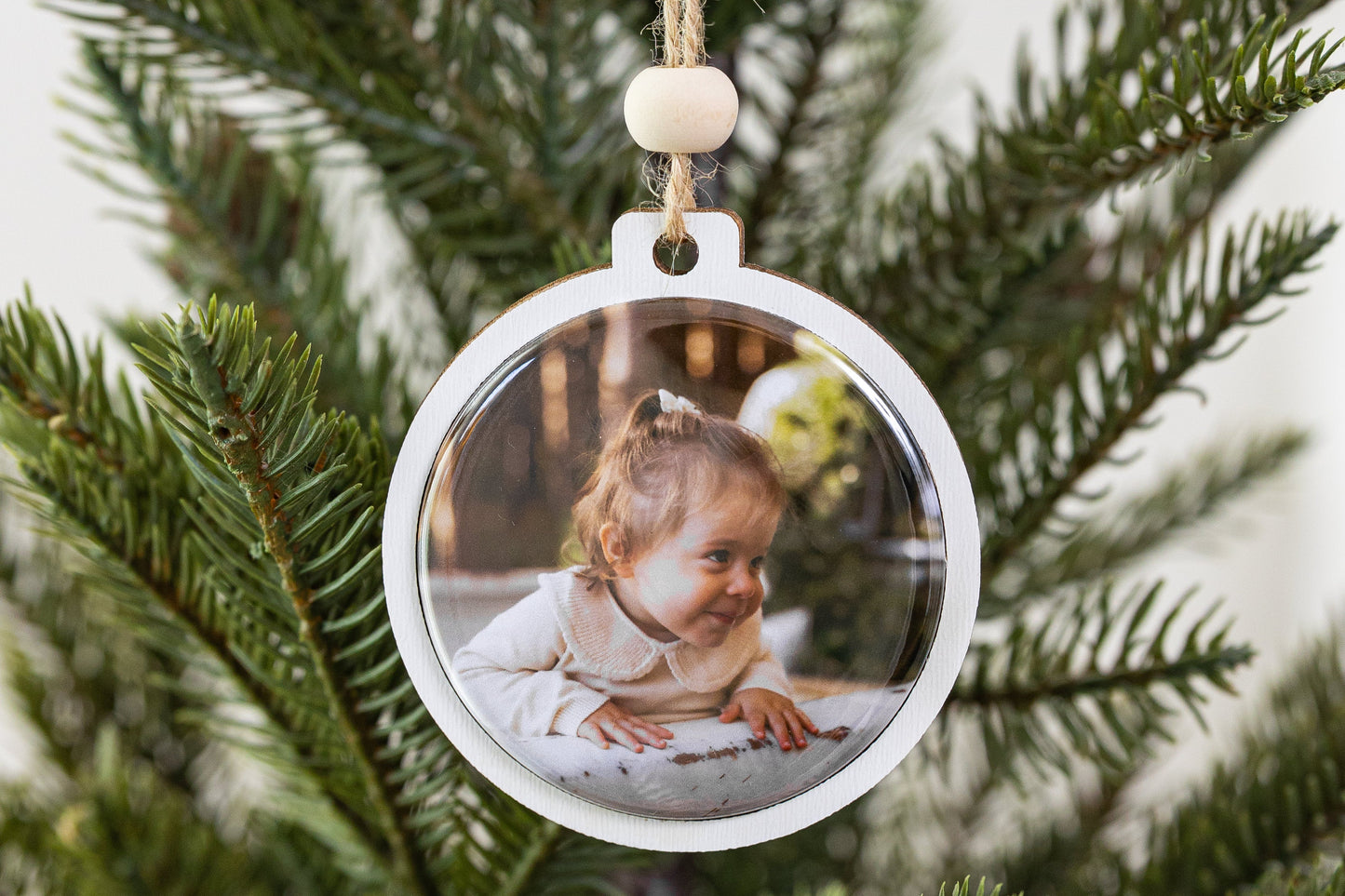 Decorative Christmas ornament with a photo of a child on a tree branch.